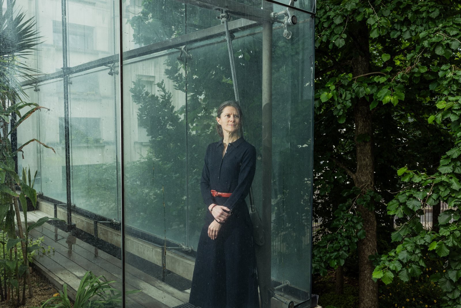 Agathe Demarais standing by a glass pavilion in a Paris garden